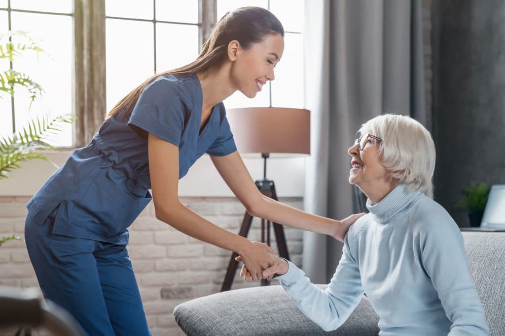 Female professional caregiver taking care of elderly woman